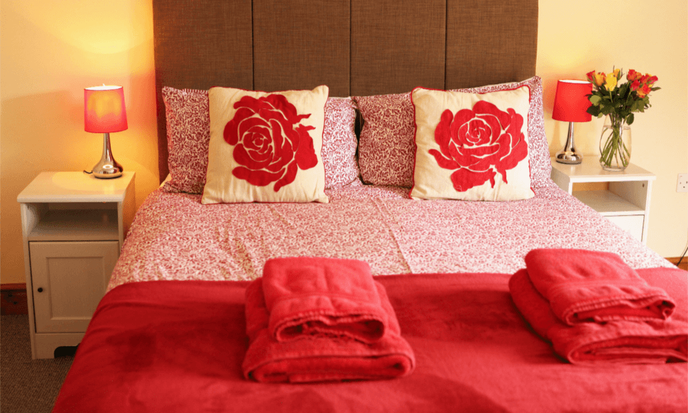 Comfy guest bed with fresh towels and cushions in Hay-on-Wye holiday cottage bedroom